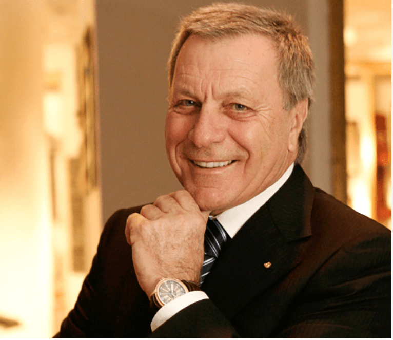 Nick smiling in a warm-toned portrait, his hand resting beneath his chin.